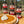Spice jars labeled 'Cinnamon', 'Cardamom', 'Nutmeg', 'Allspice', and 'Cloves' with a pumpkin pie on a wooden surface.
