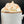 A close-up of a white ceramic mug filled with a hot beverage topped with thick whipped cream and dusted with cinnamon, set against a dark background.