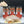 Three jars of ground cinnamon from Tradition Spice Company are displayed behind a cinnamon roll topped with cream and cocoa powder, with a whipped drink in the background on a dark studio backdrop.