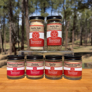 Collection of spice jars from Tradition Spice Company on a wooden surface with a natural background.