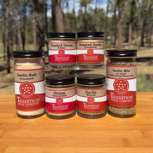 Collection of spice jars from Tradition Spice Company on a wooden surface with a natural background.