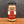 A glass jar of Tradition Spice Company Onion Minced spice blend, featuring a black lid and a red and white label, set on a wooden surface against a dark gray background.