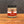 A glass jar of Tradition Spice Company Garlic Powder with a black lid, set on a wooden surface against a dark gray background.