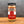 A glass jar of premium Ground Saigon Cinnamon from Tradition Spice Company sits on a wooden surface with a gray background, showcasing one of the finest baking spices for your kitchen.