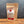 A brown resealable pouch of Tradition Spice Company Ground Saigon Cinnamon, a premium cinnamon prized among baking spices, sits on a wooden surface with a gray background. The front label describes its uses and highlights its sweet, warm flavor.