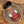 A jar of Ground Saigon Cinnamon from Tradition Spice Company sits on a ceramic dish atop a wooden surface, showcasing one of the finest baking spices for your kitchen.