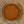 A top-down view of a glass jar filled with finely ground reddish-brown spice, identified as Ground Saigon Cinnamon, on a beige surface—perfect for adding warmth and depth to your favorite baking spices.