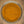 A top-down view of a fine yellow-orange powder, likely turmeric or curry powder, inside a clear glass jar.