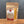 A stand-up kraft paper pouch of Tradition Spice Company Turmeric Ground, showing the yellow powder through a clear window on a wooden surface against a gray background.