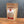 A stand-up pouch of Tradition Spice Company Brownulated Sugar standing on a wooden surface against a dark gray background. The package is made of brown kraft paper with a clear window showing the light tan sugar inside, and a white and red label on the front.