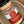 A close-up of a glass jar of Tradition Spice Company Brownulated Sugar, showing the light tan granulated sugar inside, a red and white label, and a black lid, set inside a rustic metal bowl.