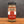 A glass jar of Tradition Spice Company Celery Salt Granulated, featuring a black metal lid and a label with red, white, and burlap textures, set on a wooden surface against a dark gray background.