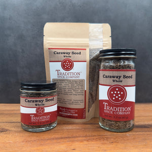 Three containers of Whole Caraway Seed are shown on a wooden surface: a small jar, a medium jar, and a brown resealable pouch, all with vibrant red and white labels.