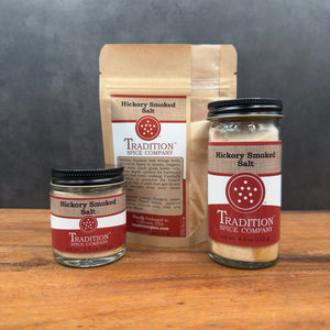 Three containers of Hickory Smoked Salt are shown—a small jar, a pouch, and a large jar—ideal for adding bold, smoky flavor to your favorite dishes or mixing up the perfect Bloody Mary.