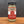 A glass jar of Whole Fennel Seed sits on a wooden surface, with a black lid and red and tan label—ideal for seasoning Italian sausage or baking rustic breads.