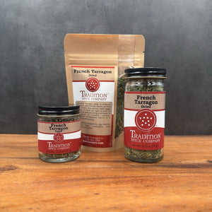 Three containers of Tradition Spice Company’s French Tarragon—a classic herb—are displayed: two glass jars and one brown resealable pouch, each with red and white labels. Ideal for adding rich flavor to your favorite dishes.