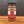 A glass jar of Za’atar, Worldly Wow! Middle Eastern Blend sits on a wooden surface, its red and white label and black lid standing out against a dark background—an authentic blend rich in sumac spice.