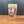 A brown resealable pouch of Za’atar, Worldly Wow! Middle Eastern Blend stands upright on a wooden surface with a gray textured background. The label features ingredients and Tradition Spice Company details in red and white text.