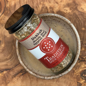 A jar of Dukkah, Worldly Wow! Egyptian Blend sits on a plate, highlighting the rich flavors of authentic Middle Eastern and Egyptian spices.