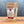 A brown resealable pouch of Sizzl’n Lime, Da Best! Chili Lime Seasoning from Tradition Spice Company rests on a wooden surface with a gray backdrop, displaying the product name and brand logo on its front label.