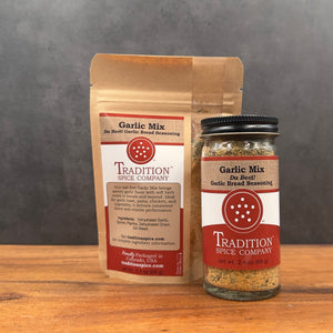 A brown resealable pouch and a clear spice jar, both labeled Garlic Mix, Da Best! Garlic Bread Seasoning, display this flavorful salt-free blend on a wooden surface with a dark gray background.