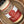 A glass jar of Granulated Garlic Salt lies on its side in a brown ceramic bowl. The label features red and beige colors with white text and a dotted circle logo.