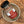 A glass jar of Tradition Spice Company Best Bruschetti Italian Appetizer Mix, featuring a black lid and a red and white label, resting inside a speckled ceramic bowl on a textured wood background.