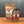 A jar and stand-up pouch of Tradition Spice Company Taste of Tuscany Bread Dip Mix displayed on a wooden surface against a dark gray background.