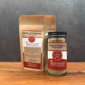 A jar and stand-up pouch of Tradition Spice Company Taste of Tuscany Bread Dip Mix displayed on a wooden surface against a dark gray background.