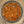 Top-down view of a seasoning blend inside a clear glass jar, showing a mixture of reddish-brown spices, herbs, and white salt crystals.