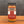 A glass jar of Tradition Spice Company Honey Garlic Sriracha Dry Rub Seasoning, filled with brown seasoning and topped with a black lid, set on a wooden surface against a dark gray background.
