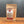 A stand-up kraft paper pouch of Tradition Spice Company Honey Garlic Sriracha Dry Rub Seasoning, displayed on a wooden surface against a dark gray background.