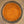 A top-down view of a clear glass jar filled with a fine brown-orange spice or seasoning blend, set on a speckled beige countertop.