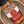 A close-up of a glass jar of Tradition Spice Company Honey Garlic Sriracha Dry Rub Seasoning, showing the spice blend through the clear container and its label, set inside a ceramic bowl.
