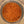 Top-down view of a clear glass jar filled with a coarse brown spice or seasoning blend on a light speckled countertop.