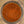 A top-down view of a spice blend in a clear glass jar, showing a textured mixture of reddish-brown, orange, and brown seasoning particles.