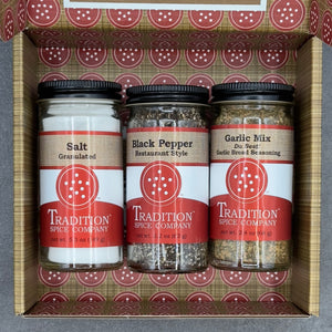 The Welcome Home Gift Box includes three Tradition Spice Company jars—salt (5.3 oz), black pepper (2 oz), and garlic mix (2.4 oz)—all featuring white and red circular-patterned labels in a decorative box.