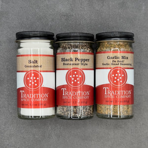 The Welcome Home Gift Box features three Tradition Spice Company jars—Salt (granulated), Black Pepper (restaurant style), and Garlic Mix—in black-lidded jars with red-and-white labels, perfect as a housewarming gift.