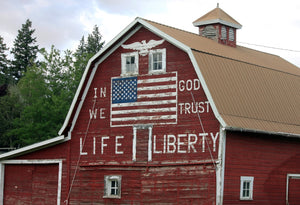 Red barn with American flag and text on a cloudy day