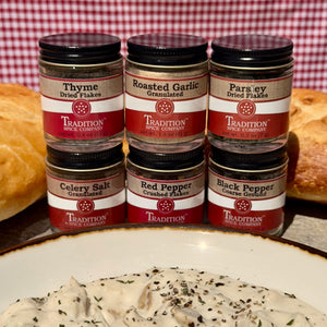 Jars of Tradition Spice Company spices with a dish of pasta in the foreground.
